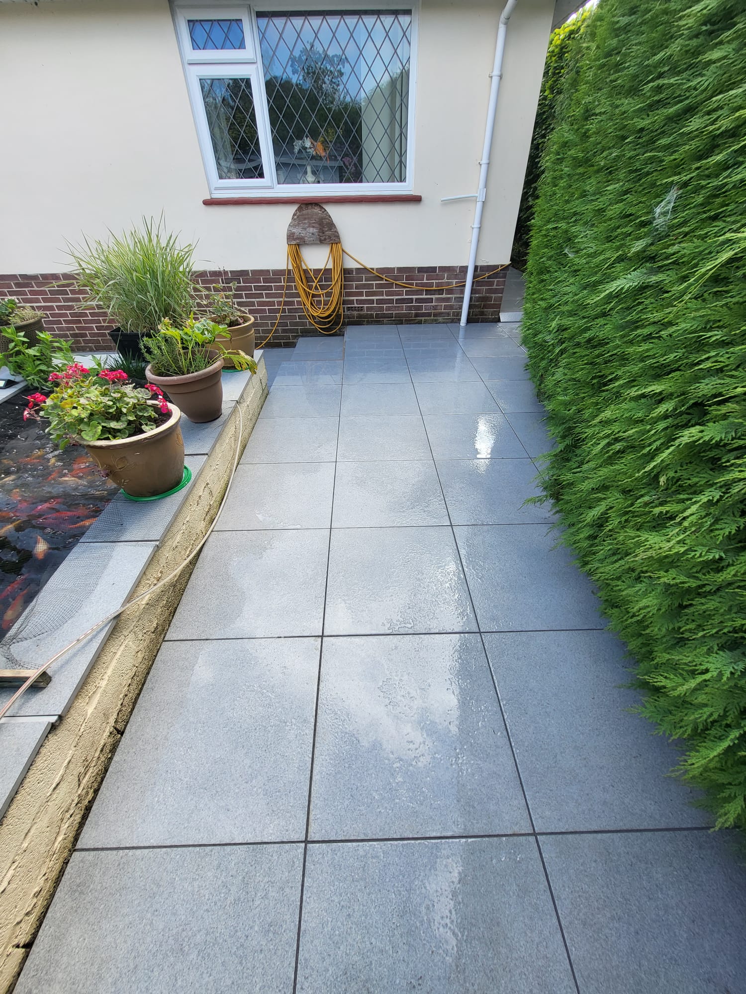 Clean tiled patio and hedge line beside a house